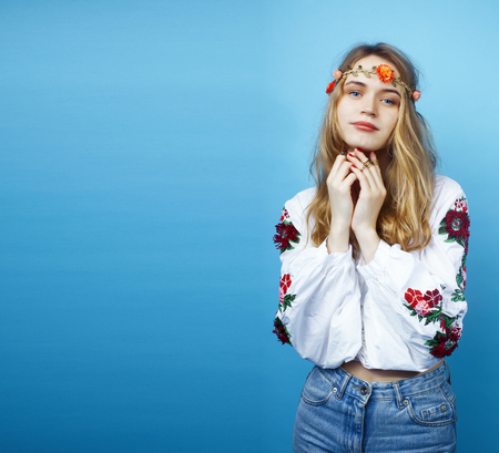 young pretty blond girl posing on blue background, fashion style hippie boho flowers on headの写真素材