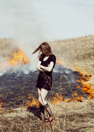 woman standing in burning field, lifestyle people conceptの写真素材