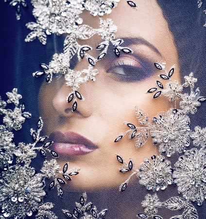 portrait of beauty young woman through lace close up mistery makeup sexy, fashion people concept closeupの写真素材