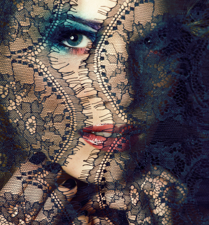 portrait of beauty young woman through lace close up mistery makeup sexy, fashion people concept closeupの写真素材