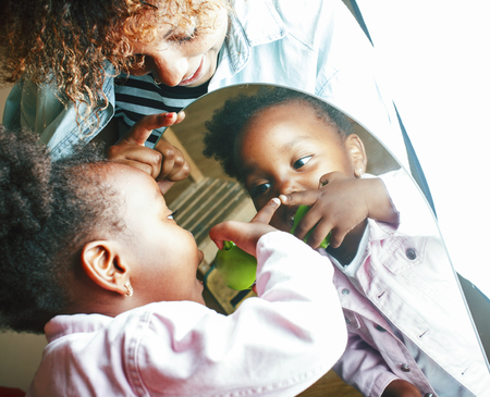 adorable sweet young afro-american mother with cute little girl, lifestyle people concept, happy family playing at homeの写真素材