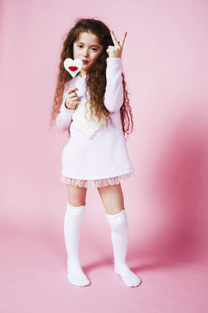 little cute girl with candy on pink background posing emotional, lifestyle people conceptの写真素材