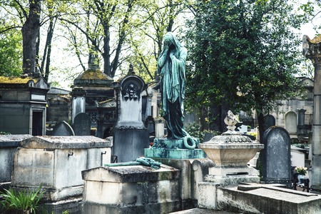 Tombstones in cemetery at dusk, gothic style crosses Parisの写真素材