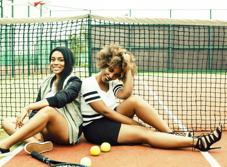 young pretty girlfriends hanging on tennis court, fashion stylish dressed swag, best friends happy smiling togetherの写真素材