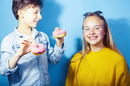 happy family brother and sister eating donuts on blue background, lifestyle people concept, boy and girl eating unhealthyの写真素材