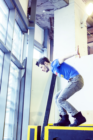 young handsome man doing parkour in gym inside, lifestyle sport people conceptの写真素材