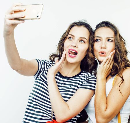 two best friends teenage girls together having fun, posing emotional on white background, besties happy smiling, making selfie, lifestyle people conceptの写真素材