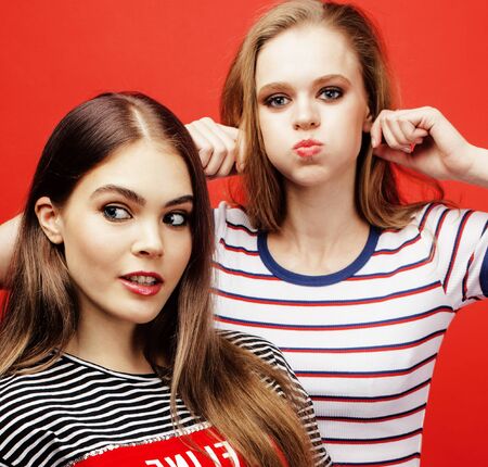 two best friends teenage girls together having fun, posing emotional on red background, besties happy smiling, lifestyle people conceptの写真素材