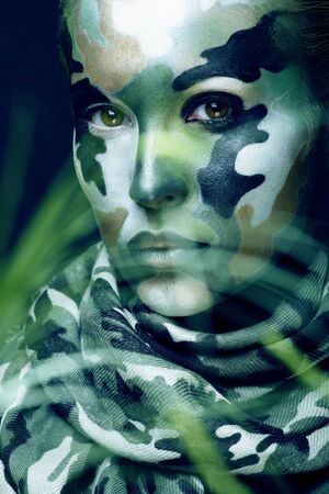 Beautiful young fashion woman with military style clothing and face paint make-up, khaki colors, halloween celebrationの写真素材