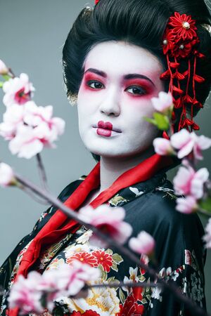 young pretty geisha in black kimono among sakura, asian ethno closeupの写真素材
