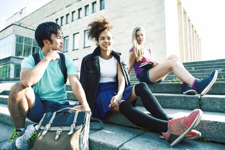 cute group of teenages at the building of university with books huggings, diversity nations real students lifestyleの写真素材