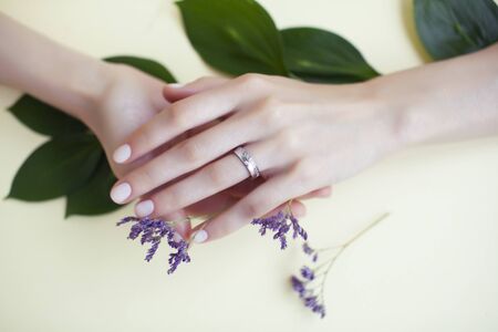 pretty perfect woman hands with white manicure and little flowers on colorful backgroundの写真素材