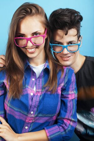 happy couple together posing cheerful on blue background wearing glasses, guy and girl students together friendsの写真素材