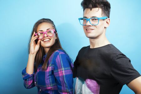 happy couple together posing cheerful on blue background wearing glasses, guy and girl students together friendsの写真素材