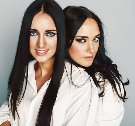 two sisters twins posing, making photo selfie, dressed same white shirt, diverse hairstyle friends, lifestyle people conceptの写真素材