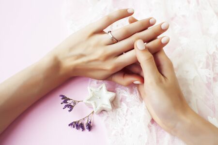 woman hands with manicure and wedding ring among white lace and little flowers closeupの写真素材