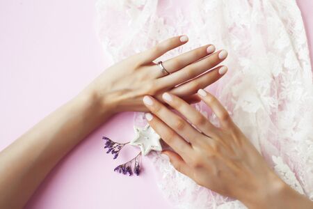woman hands with manicure and wedding ring among white lace and little flowers closeupの写真素材