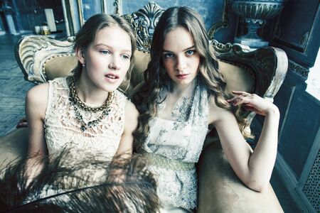 two pretty twin sister blond curly hairstyle girl in luxury house interior together, rich young people conceptの写真素材