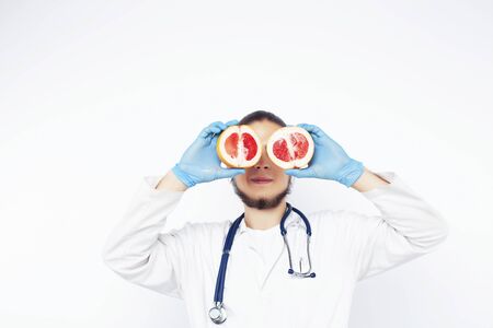 young pretty doctor with stethoscope holding fruits, vegetables and pills, syringe, healthy food care conceptの写真素材