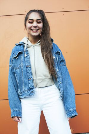 young pretty teenage girl posing cheerful happy smiling wearing street style outside in europe city,...