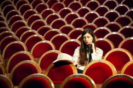portrait of a pretty girl hipster in a movie theater posing in fashion style, dreaming aloneの写真素材