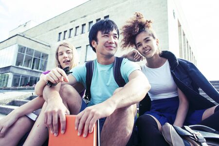 cute group of teenages at the building of university with books huggings, diversity nations real students lifestyleの写真素材