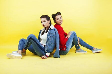 lifestyle people concept: two pretty young school teenage girls having fun happy smiling on yellow backgroundの写真素材