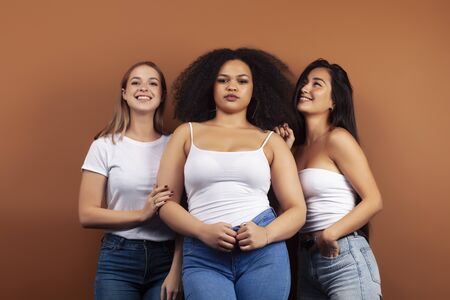 young pretty asian, caucasian, afro woman posing cheerful together on brown background, lifestyle diverse nationality people conceptの写真素材