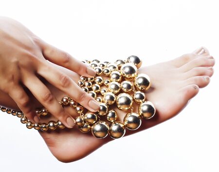 Taned hands with manicure and foot pedicured holding gold balls jewelry isolated on white background, spa salon people concept closeupの写真素材