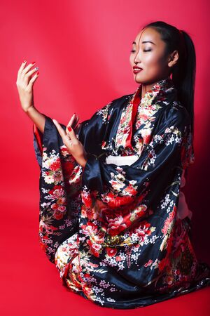 young pretty geisha on red background posing in kimono, oriental conceptの写真素材