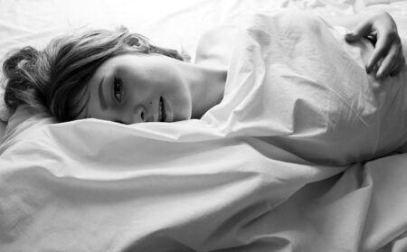 pretty blond woman laying in bed on white shits, sexy look romantic