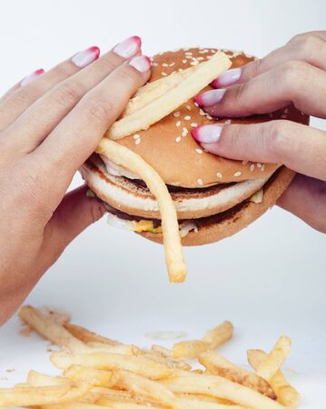 woman hand with manicure holding big burger french fries on background, people eating food concept closeupの写真素材