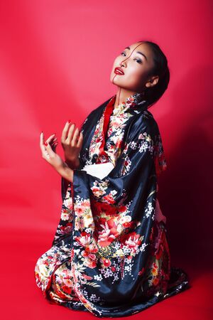 young pretty geisha on red background posing in kimono, oriental conceptの写真素材