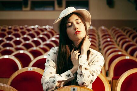 portrait of a pretty girl hipster in a movie theater posing in fashion style, dreaming aloneの写真素材