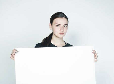 young pretty brunette girl with placard on white background wearing business costume student,...