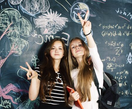 back to school after summer vacations, two teen girls in classroom with blackboard painted together