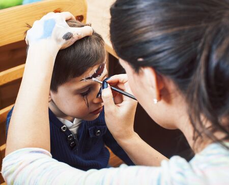 little cute child making facepaint on birthday party, zombie Apocalypse facepainting, halloween preparing concept, lifestyle peopleの写真素材