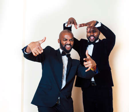 two afro-american businessmen in black suits emotional posing, gesturing, smiling. wearing bow-ties entertaiment stuffの写真素材