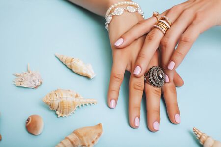 beautiful woman hands with pink manicure holding plate with pearls and sea shells, luxury jewelry concept closeupの写真素材