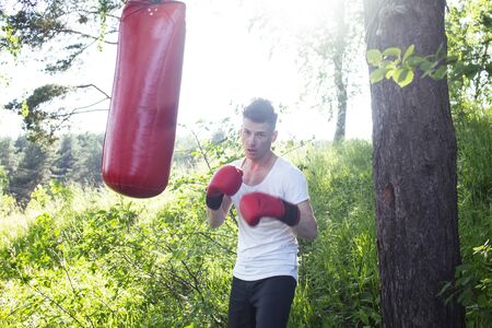 young caucasian guy boxing in gloves outside in green park, lifestyle sport people conceptの写真素材