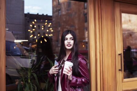 young pretty girl outside in city street with coffee happy smiling, lifestyle fashion peopple conceptの写真素材