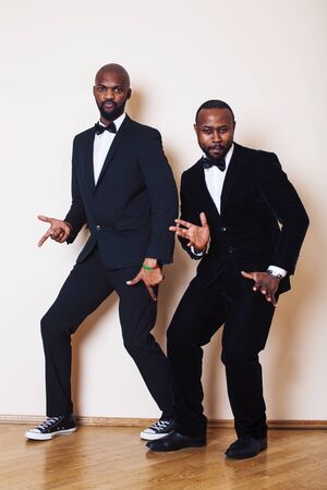 two afro-american businessmen in black suits emotional posing, gesturing, smiling. wearing bow-ties entertaiment stuffの写真素材