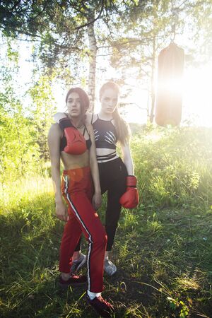 two diverse nations girls fighting boxing outside in green park, sport summer people conceptの写真素材