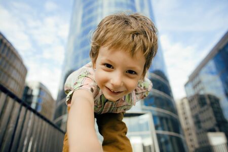 little cute boy standing near business building, smilingの写真素材