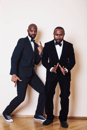 two afro-american businessmen in black suits emotional posing, gesturing, smiling. wearing bow-ties entertaiment stuffの写真素材