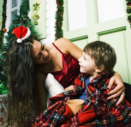happy smiling family on Christmas at house with gifts, young mother and little son in Santas red hat, lifestyle holiday people conceptの写真素材