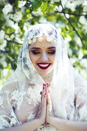 young pretty indian girl in jewelry and veil posing cheerful happy smiling in green park, lifestyle people conceptの写真素材