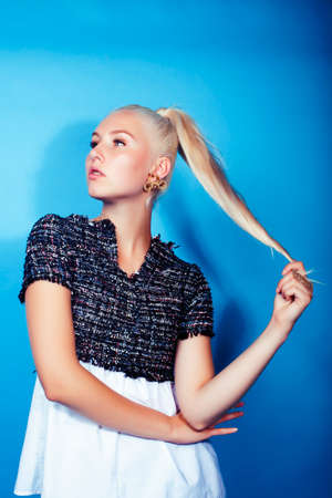 young pretty teenage modern hipster girl posing emotional happy on blue background, lifestyle people...