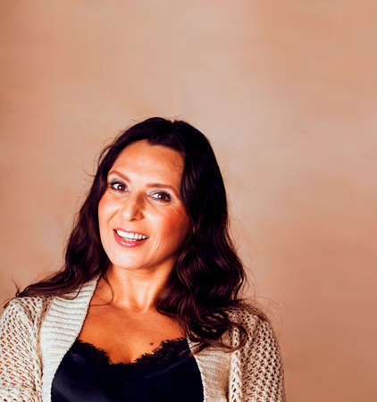 pretty brunette confident mature woman posing cheerful on warm brown background, lifestyle people...