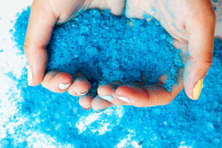 woman hands holding sea shell and sea salt with manicured nails